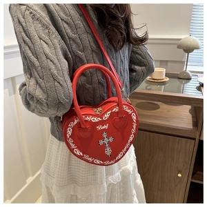 Red heart-shaped punk bag with Baby lettering and cross detail on a female model
