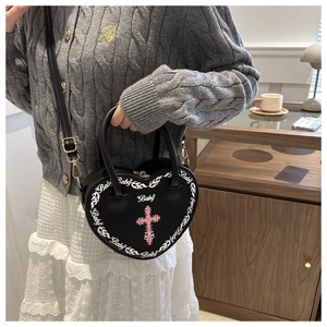 Black heart-shaped punk crossbody bag with gothic cross and flame print on a model