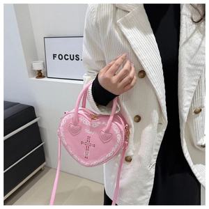 Close-up of pink heart-shaped bag featuring red cross, flame print, and Baby logo