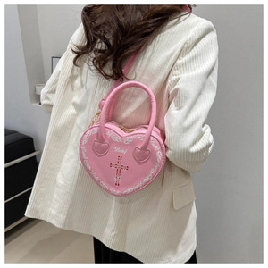 Detailed view of pink heart-shaped bag with Baby lettering and cross pattern