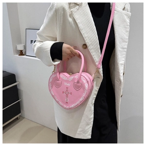 Pink heart-shaped punk bag with silver studs and cross print shown on a model