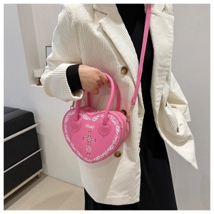 Pink heart-shaped gothic bag with Baby print and cross detail worn with a corduroy blazer