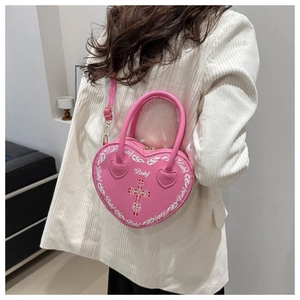 Detail der rosa herzförmigen Punk-Umhängetasche mit Kreuzdrucken, von einem Model getragen