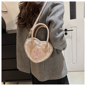 Detailed view of beige heart-shaped punk crossbody bag with cross and baby print