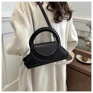 Detail of minimalist black leather handbag featuring a unique large circular handle design
