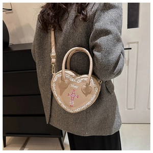 Crossbody beige heart bag with red cross and Baby print worn by model in grey suit
