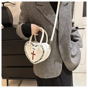Detail of white heart-shaped bag with red cross print and baby typography design