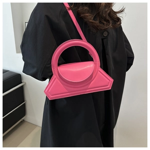 Pink leather handbag with large round handle styled on a black coat for high contrast