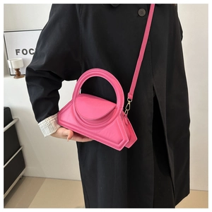 Detail of a bright pink geometric triangular handbag with a smooth leather texture