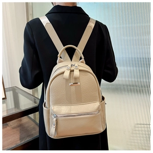 Detail of cream faux leather backpack showing litchi texture and silver metal zippers