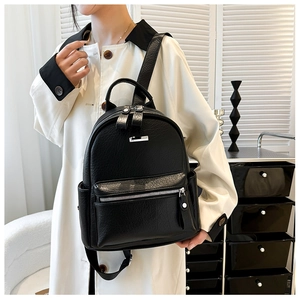 Close-up of black lychee-textured leather backpack on a model showing detailed pockets