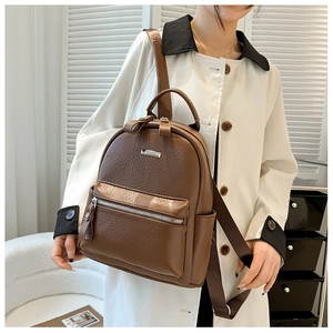 Close-up of the dark brown lychee textured leather and silver zipper on the backpack