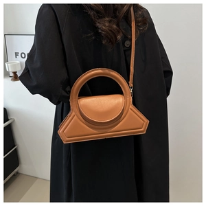 Close-up of brown leather geometric handbag with unique round handle and trapezoid base