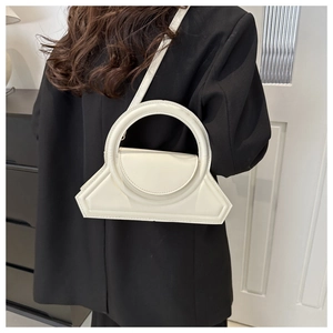 Detail of white minimalist handbag with large circular handle and magnetic flap closure