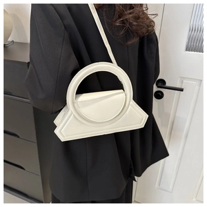 Detail of cream-colored geometric leather handbag with a circular top handle design