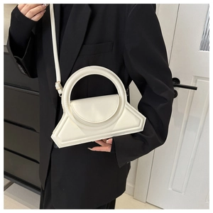 Detail view of a white geometric handbag featuring a round handle and slender strap
