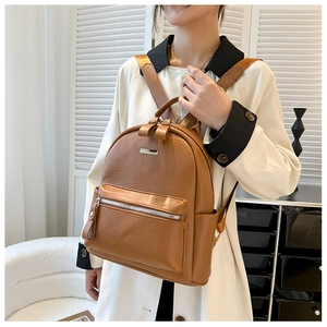 Detail view of brown faux leather backpack texture with silver zippers and side pockets
