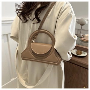 Close-up of khaki geometric leather handbag featuring a unique circular metal handle