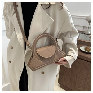 Detail view of khaki geometric tote bag with large round handle on a white coat