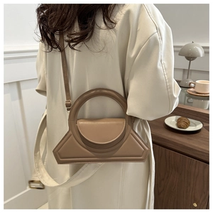Chique bruine geometrische crossbodytas met rond handvat op model in een minimalistische setting