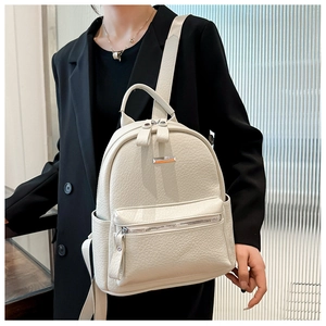 Detail of soft cream-white leather backpack with lychee grain texture on a black blazer