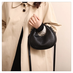 Detail view of a black woven leather crescent bag with a detachable shoulder strap
