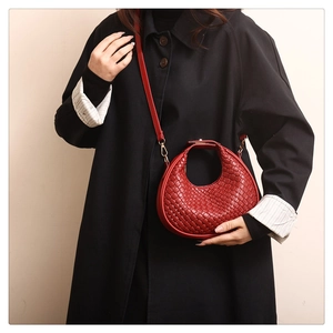 Dettaglio borsa hobo intrecciata rossa su trench nero con tracolla regolabile