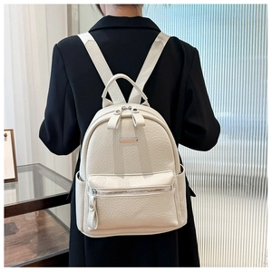 Close-up of beige lychee-patterned leather backpack worn by a model in a modern interior