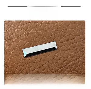 Detailed macro shot of brown lychee grain PU leather with a silver rectangular metal buckle