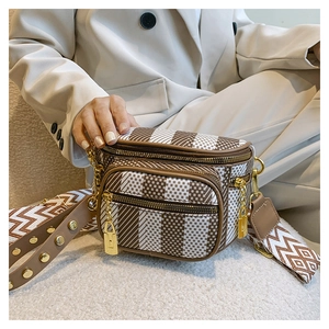 Detail of checkered crossbody bag with vintage wide strap and gold hardware on model