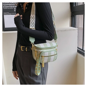 Detail of mint green striped crossbody bag with multi-zipper and wide fabric strap