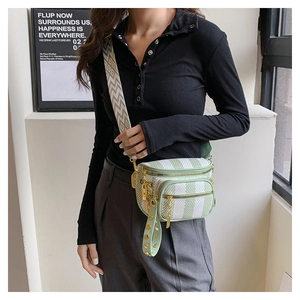 Detail of light green striped crossbody bag with wide jacquard strap and gold hardware