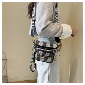 Detail view of black and white patterned crossbody bag with gold zippers and woven strap