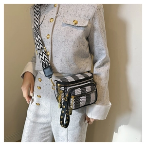Detail view of black and white checkered crossbody bag with stylish wide patterned strap
