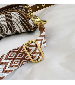 Detail of adjustable geometric patterned woven strap with gold metal buckle on a crossbody bag