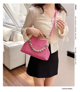 Detail of pink woven handbag with wooden handle and chunky gold metal chain link
