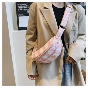 Pink and white checkered crossbody bag with wide geometric strap worn on a beige blazer