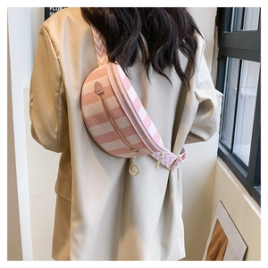 Close-up of pink geometric crossbody bag with gold charms and patterned shoulder strap