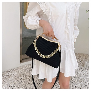 Chic black pleated handbag with gold chain detail on elegant white dress outfit