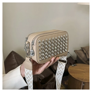 Detailed close-up of a beige camera bag with sparkling rhinestones and wide strap