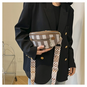 Detail of a brown and white semi-circle crossbody bag with wide geometric strap