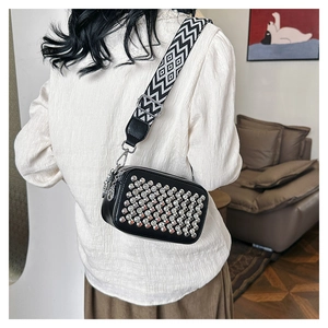 Detail of black crossbody bag with silver studs and geometric patterned wide strap