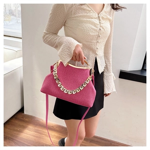 Detail of fuchsia woven handbag featuring a gold chunky chain and metallic frame clasp