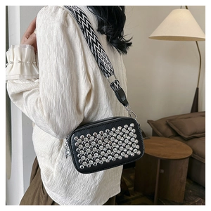 Detail of black crossbody bag with silver rhinestones and wide geometric pattern strap
