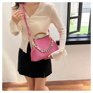 Detail of pink woven crossbody bag with wooden handle and rhinestone gold chain
