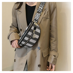 Detail of checkered crossbody bag with multiple metal zippers and geometric strap worn by model