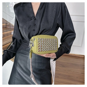 Detail of lime green camera bag featuring rhinestone studs and wide geometric strap