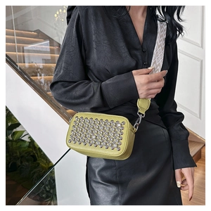 Detail of neon lime crossbody bag with silver studs and wide geometric strap
