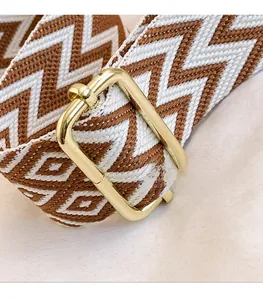 Detailed shot of chevron woven strap with adjustable gold buckle and brown textile pattern