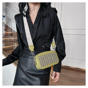 Detail of green rhinestone crossbody bag with wide wavy patterned shoulder strap on model